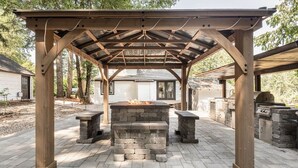 A wooden pergola with a brick fire pit and benches, surrounded by a paved patio and stone walls. - Farmhouse on wine scenic route, alpacas and hot tub. Pet friendly.  (Hillsboro)