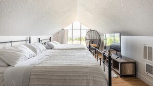 A bedroom with two beds, a chair, a small table, and a large window. - Farmhouse on wine scenic route, alpacas and hot tub. Pet friendly.  (Hillsboro)