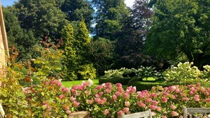 Un jardí amb mur de maó i cadires de fusta.