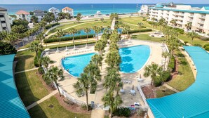 Un complexe hôtelier doté d’une grande piscine, de palmiers et offrant une vue sur l’océan.
