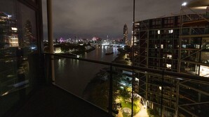 A nighttime cityscape with a river, modern buildings, and a construction site. - River Side View Luxury Penthouse Apartment (London)