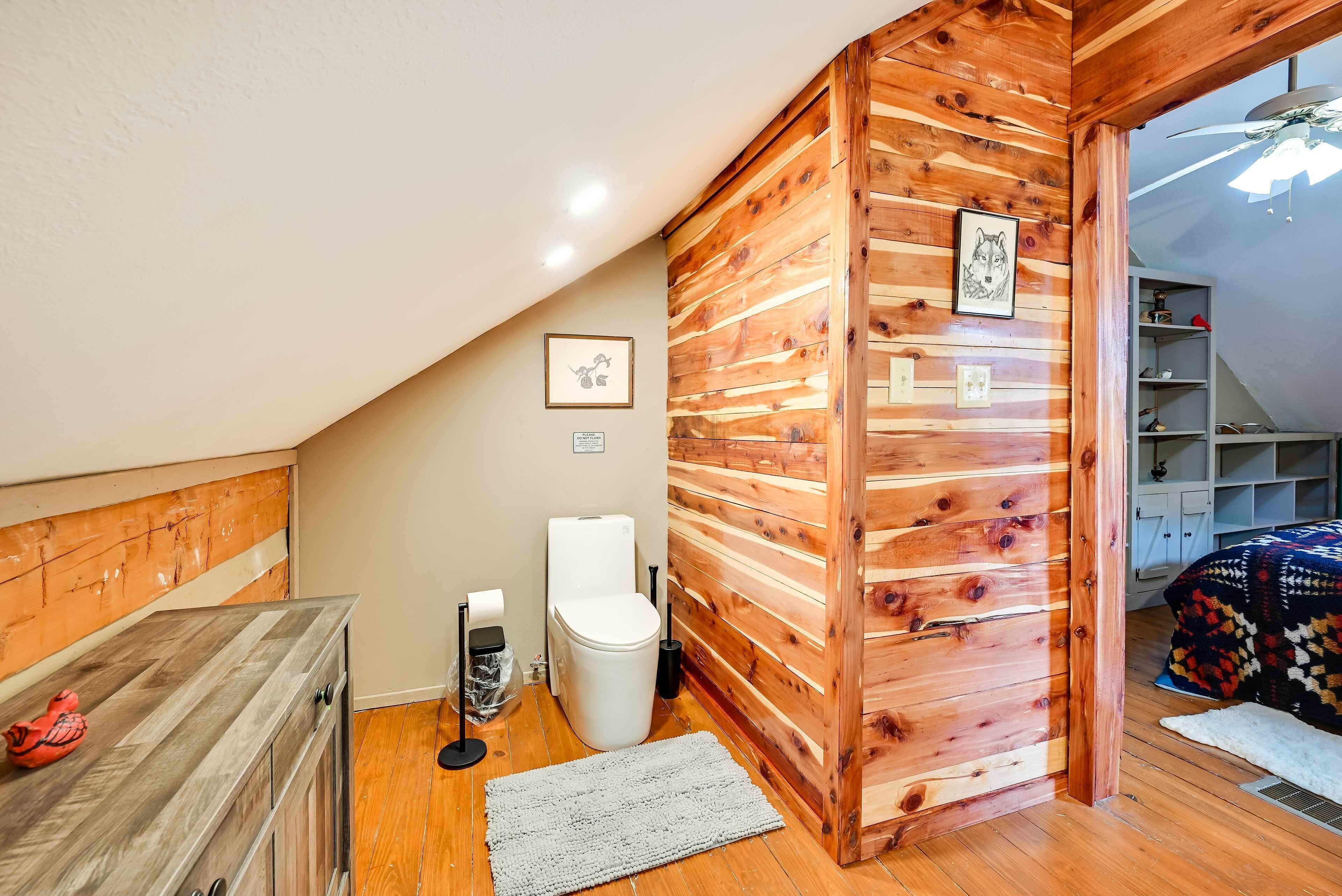 A small, cozy room with wooden walls, a white toilet, and a wooden cabinet.
