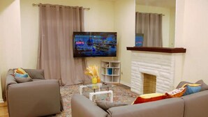 A living room with a flat-screen TV, a fireplace, and two sofas. - Spacious 5BR/5BA Group Stay w/Game Room + Parking, Sleeps 12, Central Location (Pittsburgh)