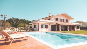 A two-story house with a swimming pool, outdoor furniture, and a clear sky.