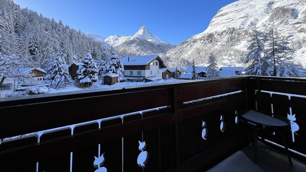 Un paysage de montagne enneigé, avec un bâtiment de style chalet au premier plan.
