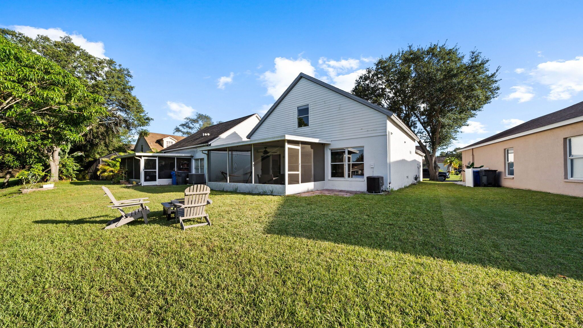 A two-story house with a covered patio, a lawn, and a tree.