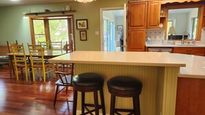 Una cocina con armarios de madera, una isla grande con taburetes y un comedor con sillas.