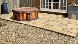 A backyard with a wooden hot tub, a brick house, and a wooden fence. - French Vintage Cottage in the Heart of the Fens (Spalding)