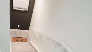 A staircase with white railings and a wooden floor. - Luxury Living Basement suite (Calgary)