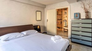 Een hotelkamer met een bed, een kledingkast, een spiegel en een deur naar een inloopkast.