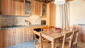 Een keuken met houten kastjes, een eettafel en stoelen.