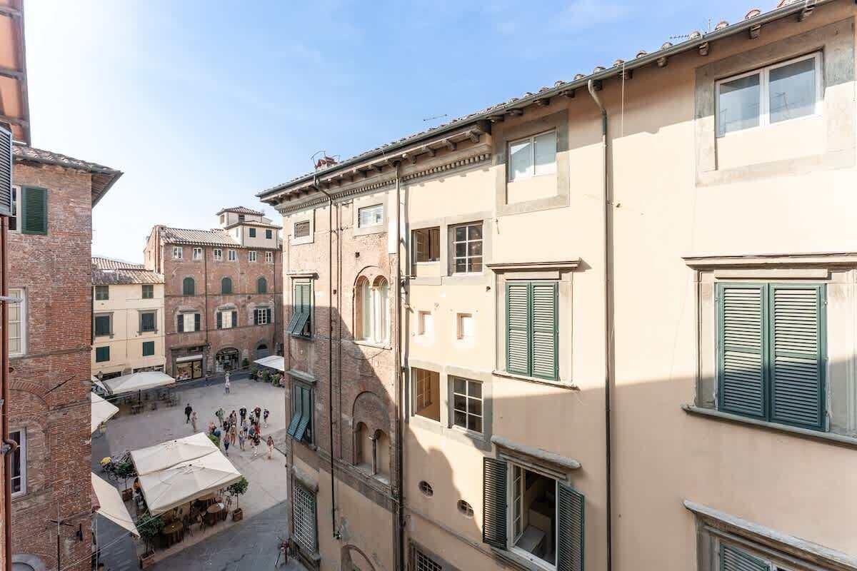 A courtyard with buildings, outdoor seating, and a clear sky.