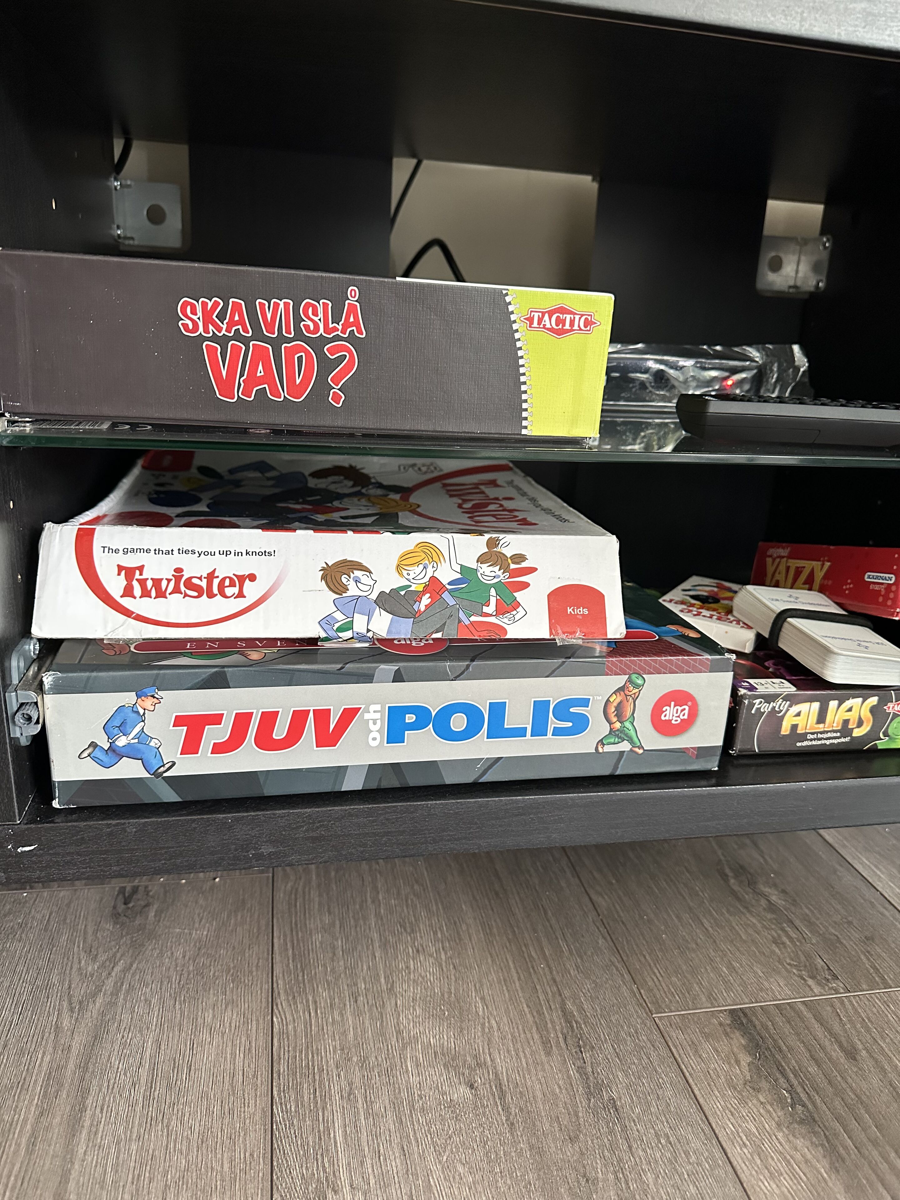 A shelf with board games including 'Twister' and 'TJUv POLIS'.