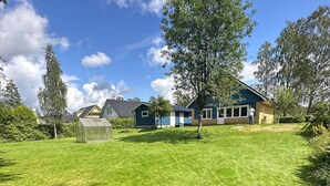 A residential area with a large green lawn, a greenhouse, and a house with a blue exterior. - Modern house for 6 people - close to Gekås Ullared (Hallands län)