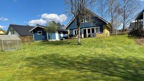 A residential area with a well-maintained lawn, a greenhouse, and houses with blue and yellow exteriors. - Modern house for 6 people - close to Gekås Ullared (Hallands län)
