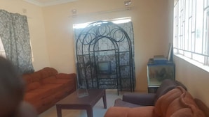 A living room with a sofa set, a coffee table, and a television. - fish eagle backpackers (Lusaka)