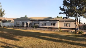 A two-story house with a flat roof and a large front lawn. - fish eagle backpackers (Lusaka)