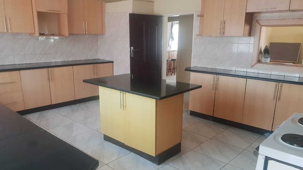 A kitchen with light wooden cabinets, a central island with a black countertop, and a white stove. - fish eagle backpackers (Lusaka)