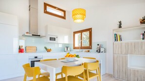 A modern kitchen with white cabinets, a wooden dining table, and yellow chairs.