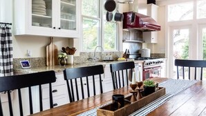 A kitchen with a wooden dining table, chairs, and a stove. - Red House Paso- Modern Farmhouse Downtown (Paso Robles)