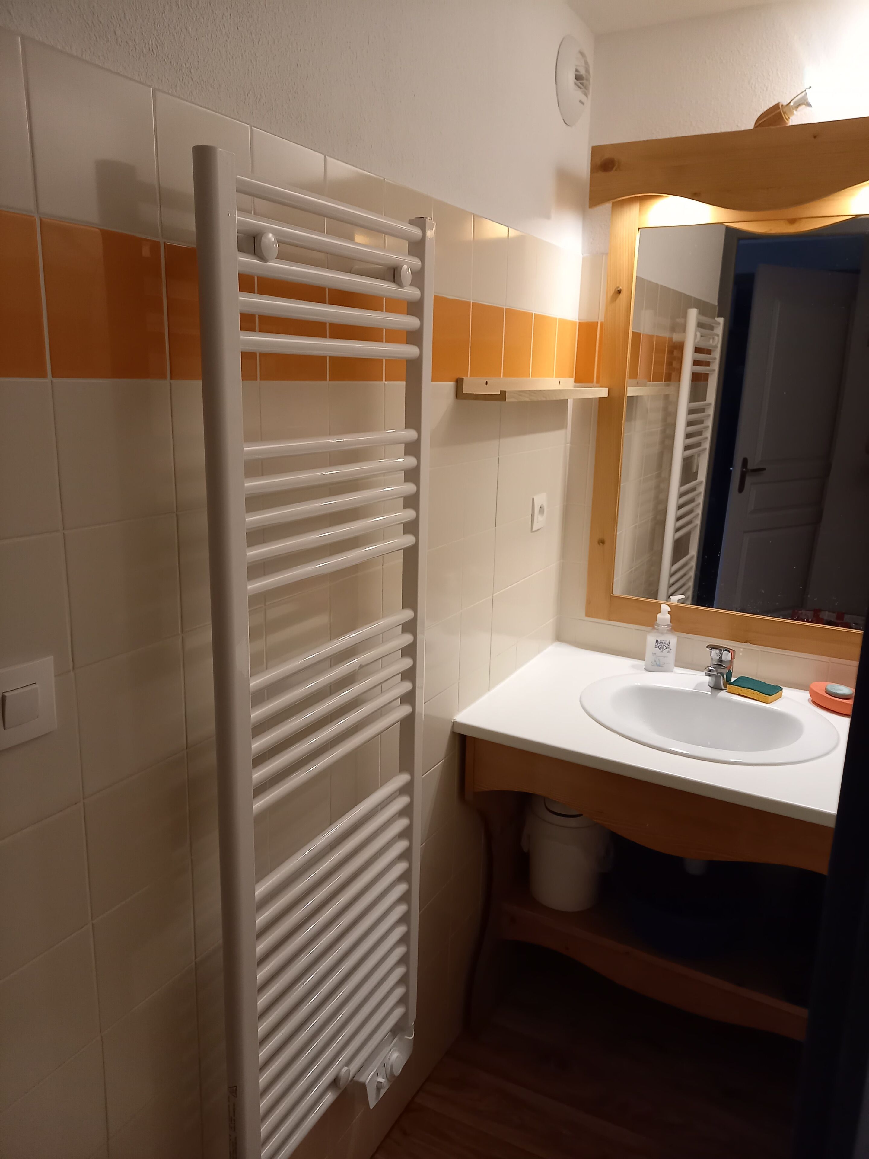 A bathroom with a white sink, a mirror, and a towel rack.