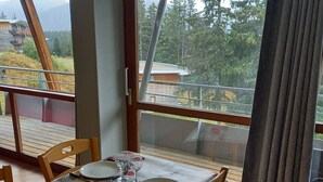Een eetgedeelte met een tafel voor vier personen, uitzicht op de omgeving en een raam met gordijnen.