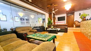 Ein Wohnzimmer mit einer Couch, Sesseln, einem Couchtisch und einem Fernseher.