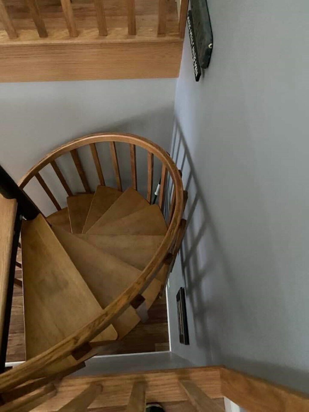Eine Wendeltreppe aus Holz mit Handlauf und einer Wandleuchte.