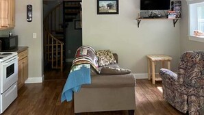 Ein Loft-Wohnzimmer mit Holzbalkendecke, einer Couch, einem Fernseher und einer Treppe zu einer oberen Ebene.