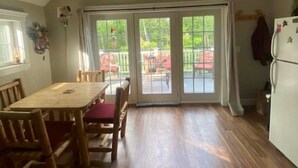 Ein Essbereich mit Holztisch und -stühlen, einer Holzbalkendecke und Blick durch Glastüren auf eine Außenpatio.