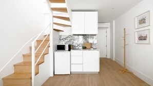 Una cocina moderna con armarios blancos, una escalera de madera y un salpicadero de mármol.