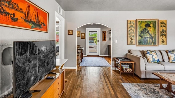 A living room with a TV, sofa, and artwork. - Mid-Century Retreat | Private Pool+Pet Friendly (Tucson)