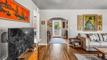 A living room with a TV, sofa, and artwork.
