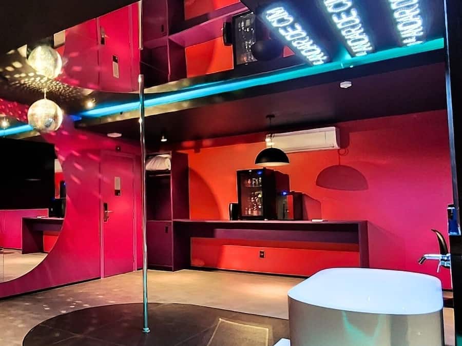 A modern interior with a curved red wall, a round white table, and a black floor lamp.