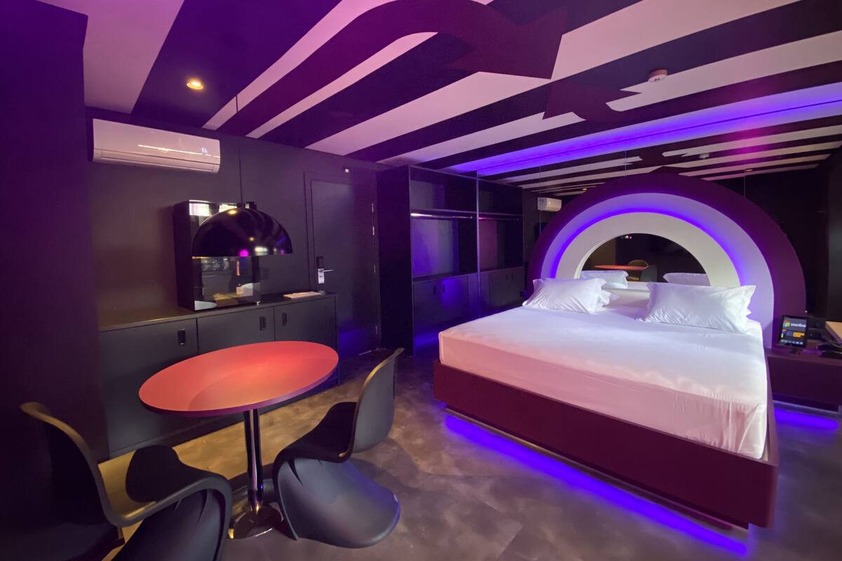 A modern hotel room with a bed, a desk, and a chair.