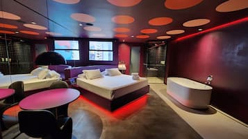 Relax in a spacious room with a large bed, separate seating area, and bathtub.