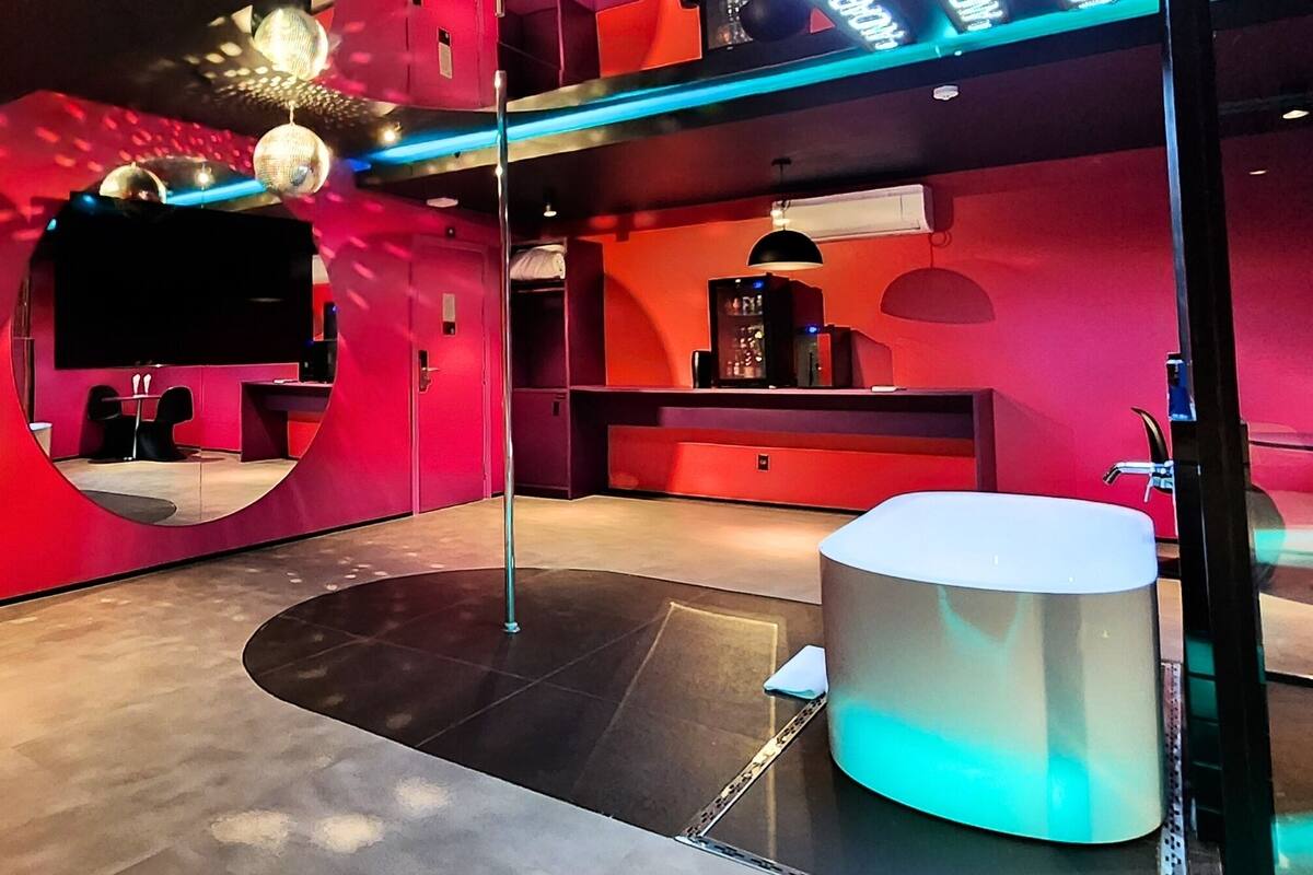 A modern room with a curved mirror, a round white table, and a red accent wall.