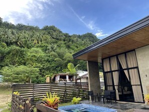 Un bâtiment moderne doté d’une piscine, entouré d’une végétation luxuriante et d’une clôture en bois.