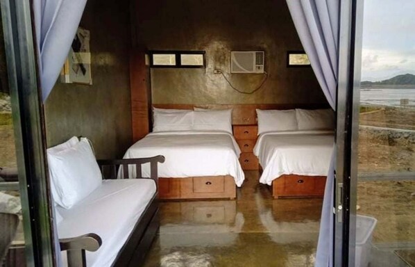 Une chambre avec deux lits, une fenêtre et un appareil de climatisation.