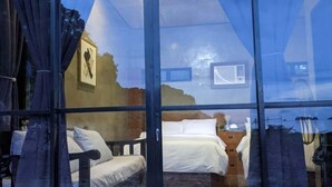 A room with a bed, a desk, and a chair, with curtains on the windows. - Villa Overlooking the Bay at Crystal Cove (Sipalay, Negros Occidental)