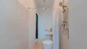 En smal gang med toilet og bruseområde.