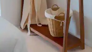Et træophæng med en hvid morgenkåbe og et par slippers på en træhylde.