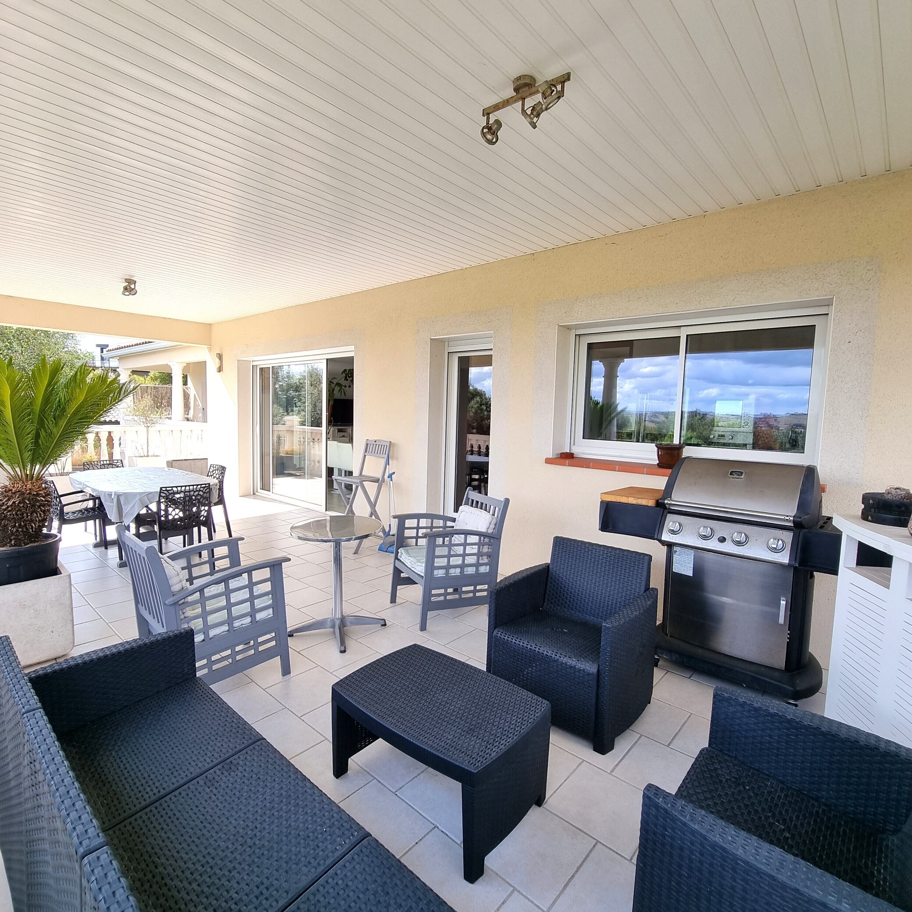 Un patio al aire libre con mobiliario de mimbre, una parrilla y vistas del paisaje.