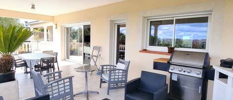 Un patio al aire libre con mobiliario de mimbre, una parrilla y vistas del paisaje.