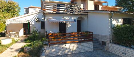 A two-story house with a patio area, outdoor seating, and a small garden.