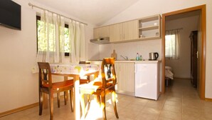 A compact kitchen with a dining area, a small refrigerator, and a television mounted on the wall. - Apartment 1778/20511 (Istria - Kukci), 2000m from the beach (Kukci)