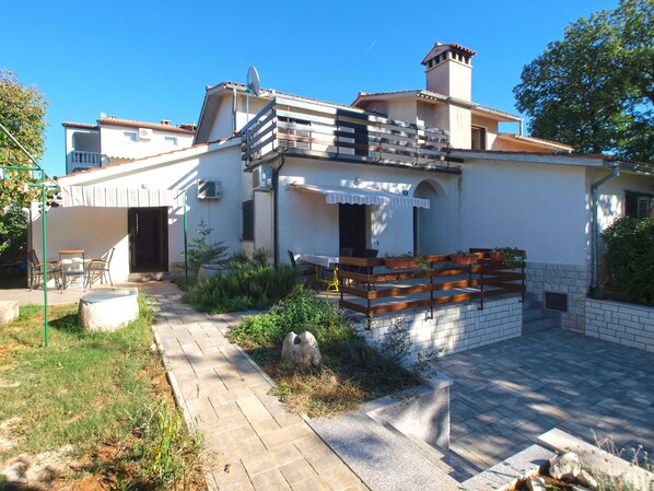 Stylish building with a flat roof and chimney, featuring a balcony and outdoor seating area with potted plants.
