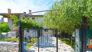 A gated entrance with a stone pathway leading to a building with a tiled roof and a tree-lined street. - Apartment 2265/75351 (Istria - Pula), 500m from the beach (Pula)