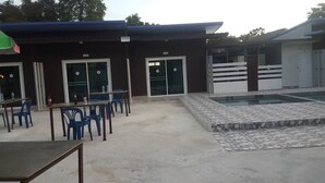 Un bâtiment doté d’un patio couvert, d’un espace extérieur aménagé avec des tables et des chaises, et d’une petite piscine avec une terrasse carrelée.