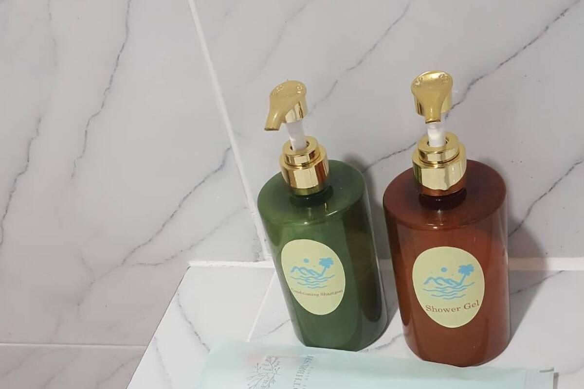 Deux bouteilles de gel douche sur une surface carrelée en marbre, avec un mouchoir en papier à proximité.